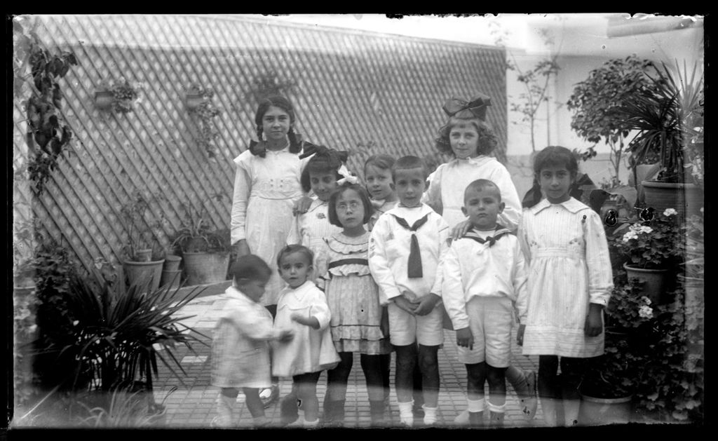 NIÑOS DE BLANCO EN EL PATIO DE MACETAS.