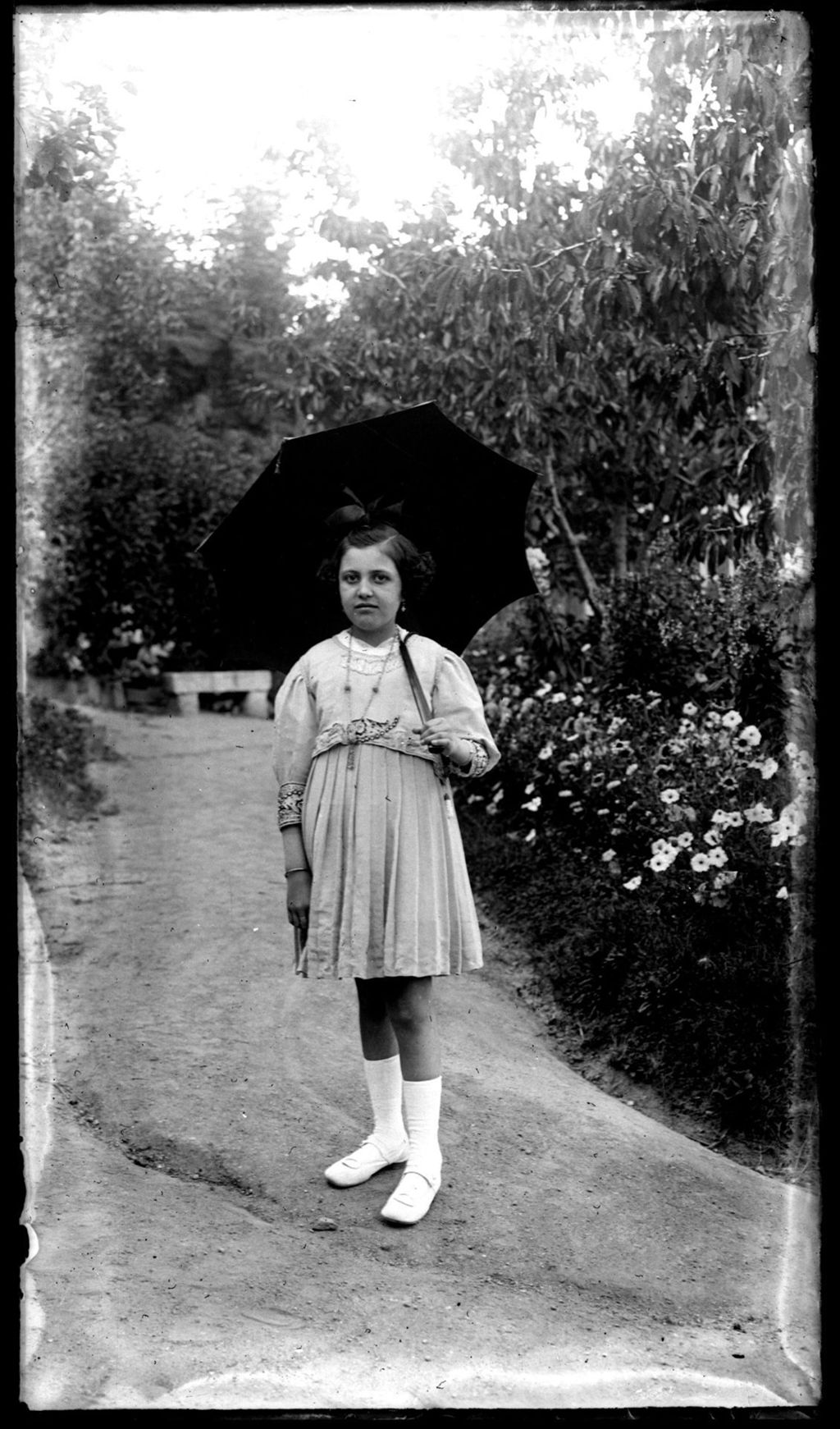 NIÑA CON PARASOL EN EL JARDIN.