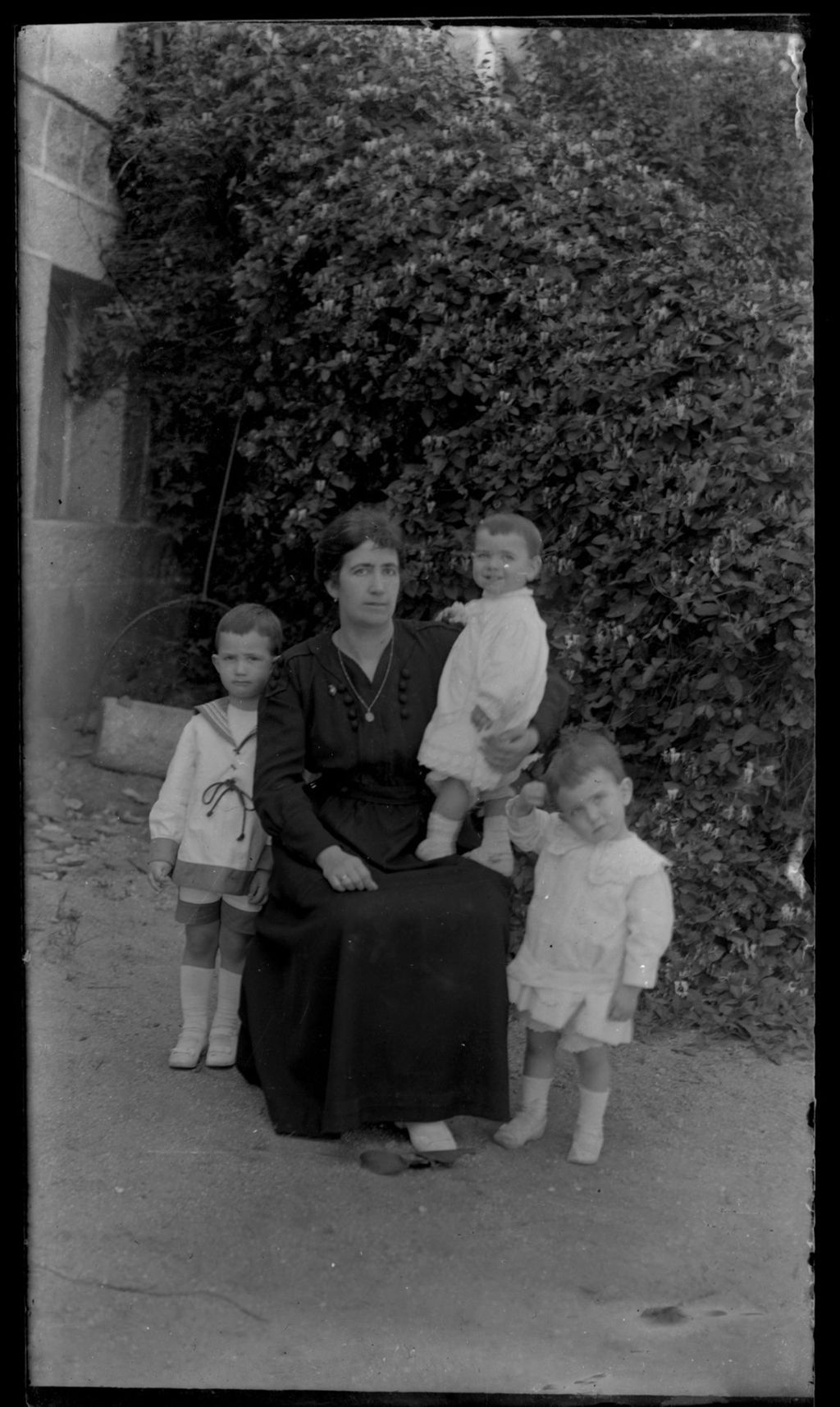 MUJER CON TRES NIÑOS EN EL JARDIN.