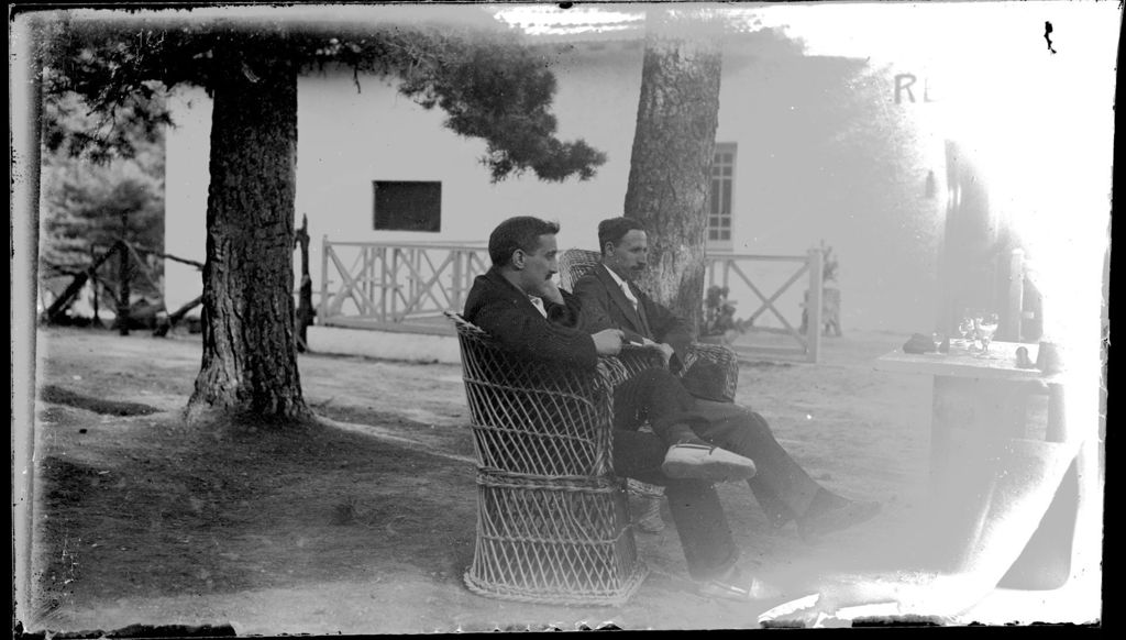 HOMBRES SENTADOS EN BUTACAS DE MIMBRE.