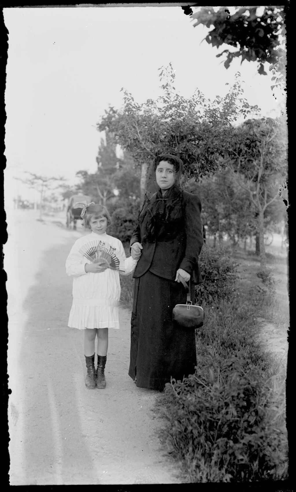 IMAGEN DE MADRE E HIJA CON CARRUAJE AL FONDO.