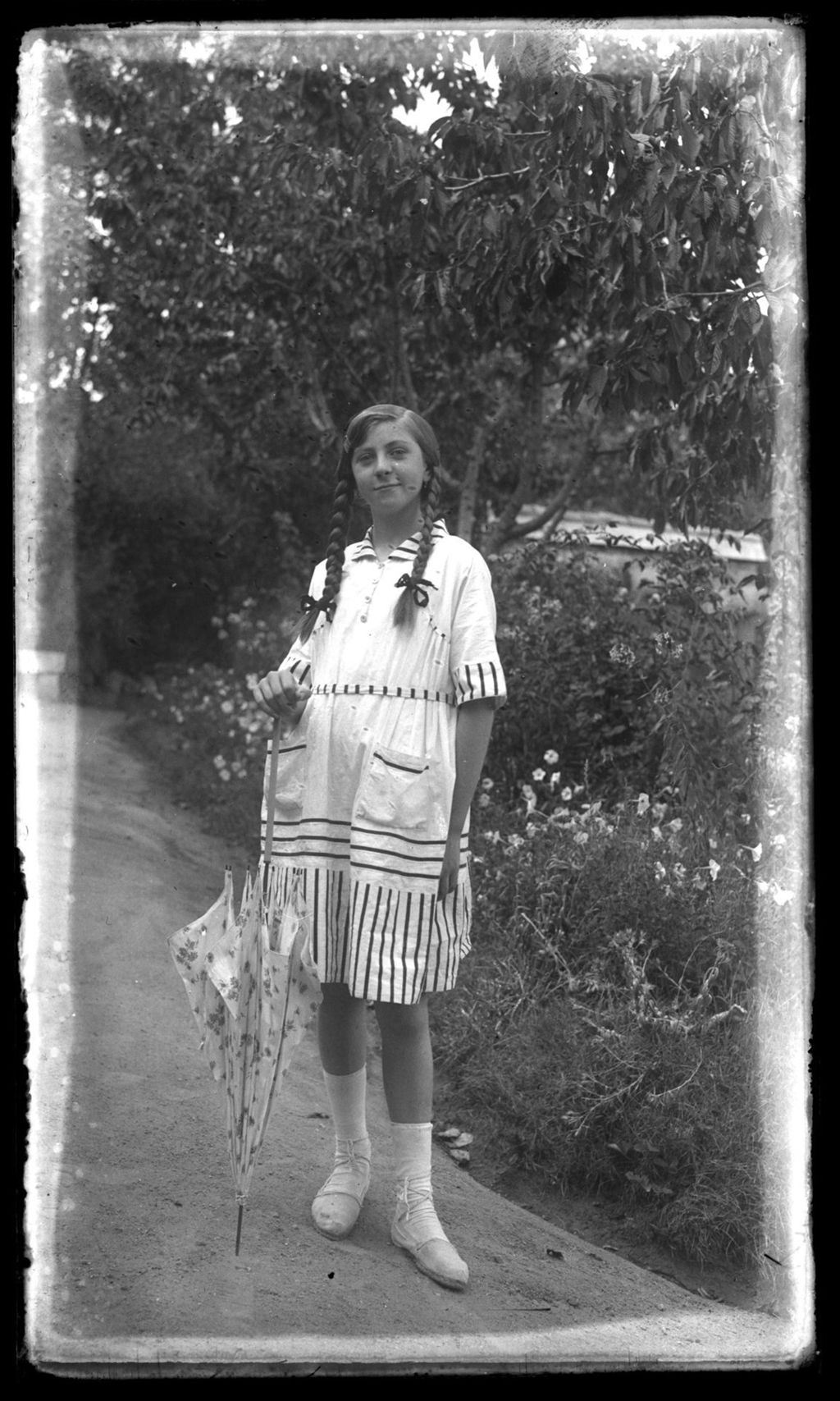 NIÑA RUBIA CON TRENZAS Y PARASOL.