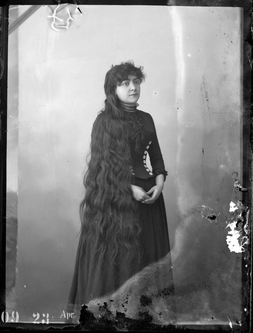 MUJER DE PELO LARGO Y VESTIDO OSCURO.